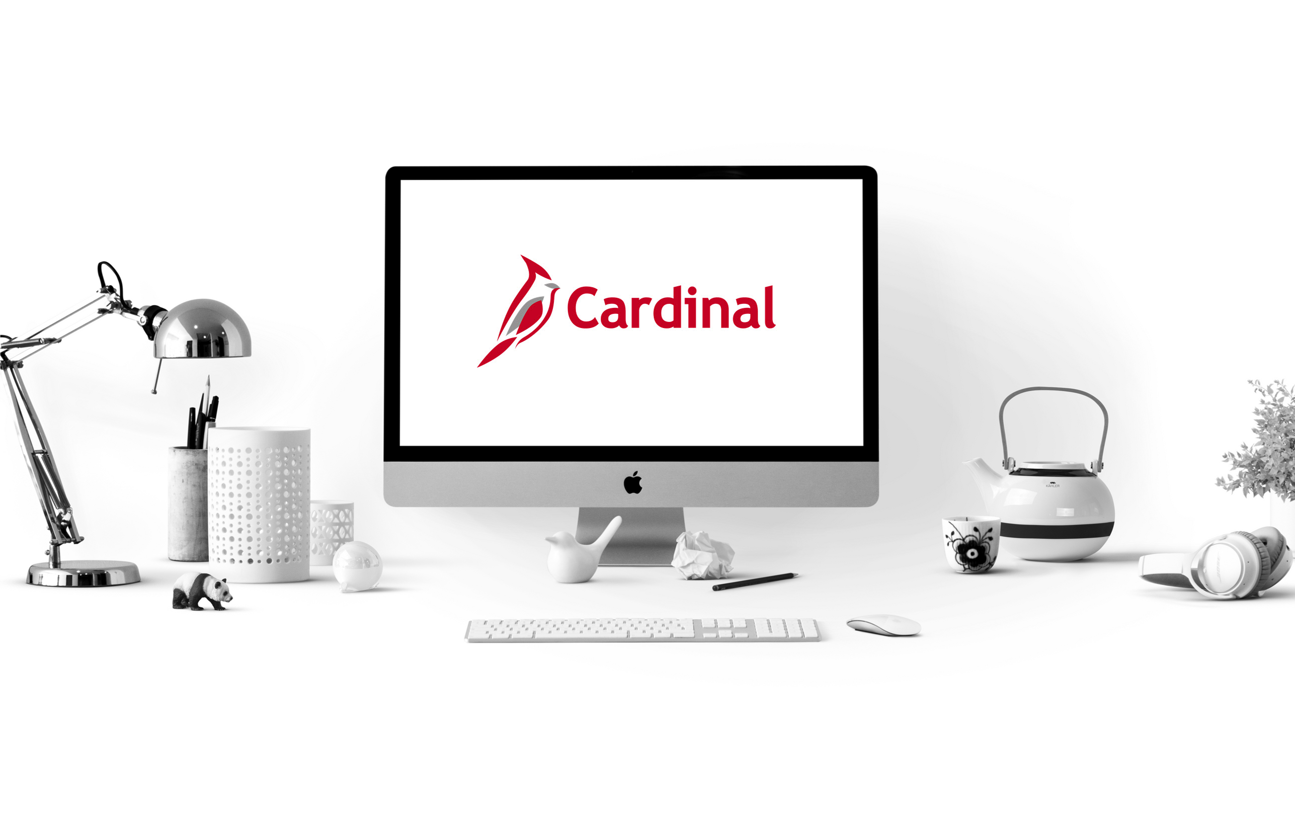 Image of a workstation with a computer that has the Cardinal logo on screen. The computer is surrounded by desk items.