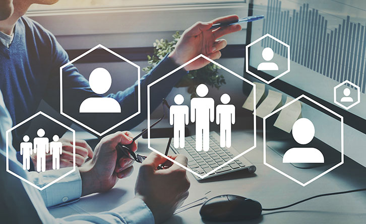 Decorative image - people pointing to computer with a graphic overlay of hexagons with people icons within.
