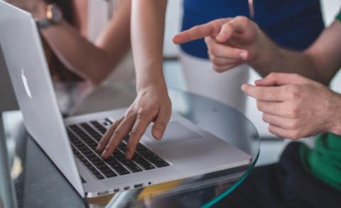 Person typing and pointing at computer